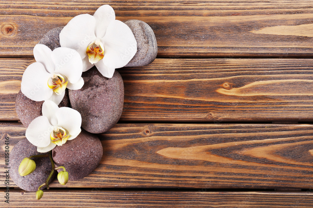 Spa stones and orchid flower on wooden background Spa stones and orchid flower on wooden background