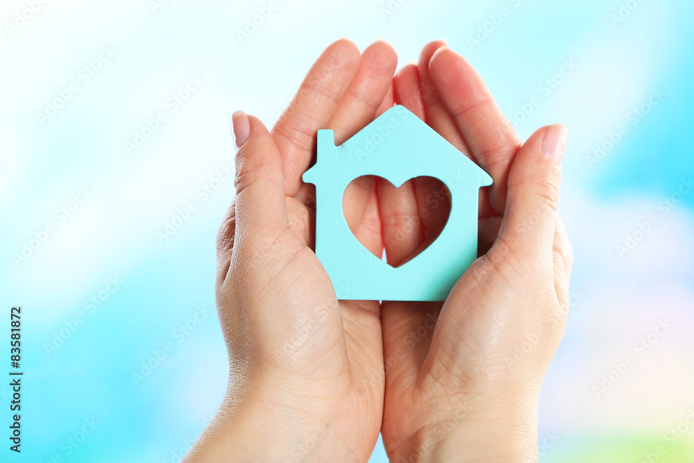 Fototapeta premium Female hands holding model of house on bright background