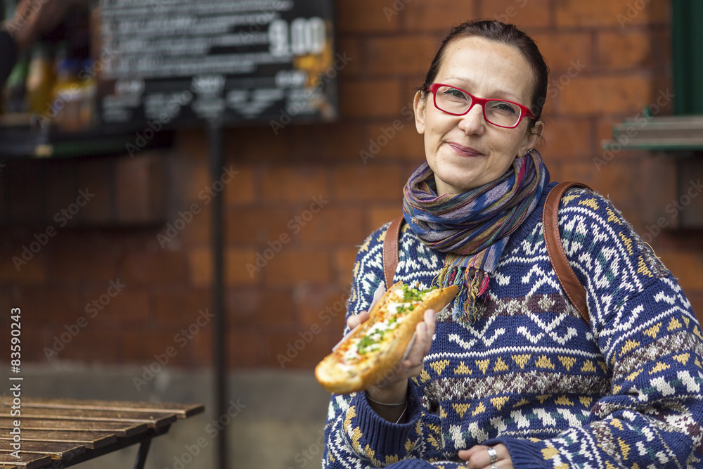 Obraz premium Woman eating Zapiekanka - Polish fast-food a casserole.
