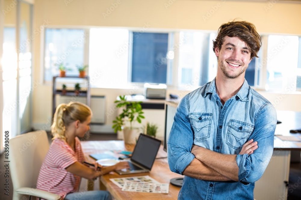 Fototapeta premium Smiling businessman posing with his partner behind him