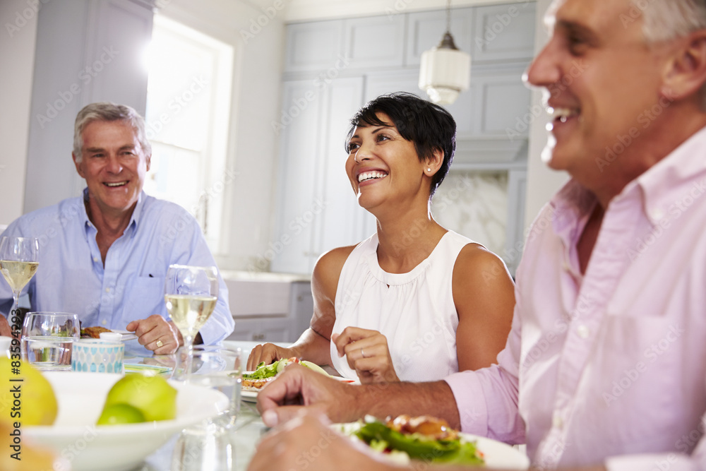 Group Of Mature Friends Enjoying Meal At Home Together