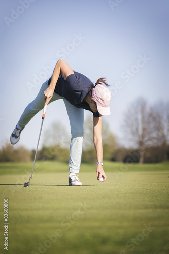 Woman golf player pick up ball.