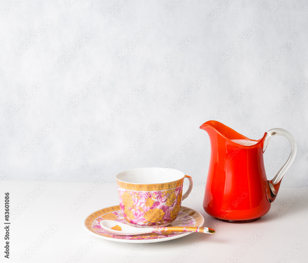 Fototapeta premium antique cup and saucer and milk in a glass jar orange