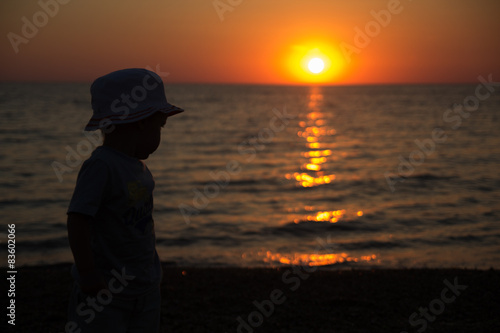 little boy standing back and enjoy the sunset on the sea