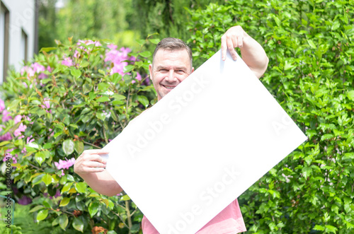 Junger Mann zeigt ein leeres weißes Plakat