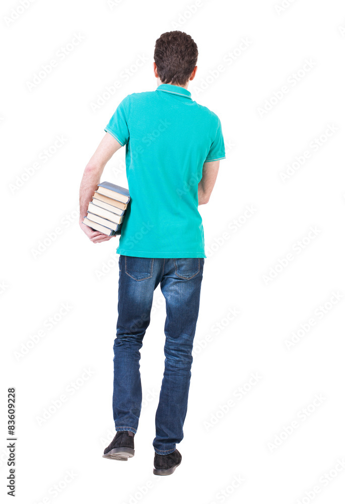 Back view of going handsome man carries a stack of books. Back view of going handsome man carries a stack of books.