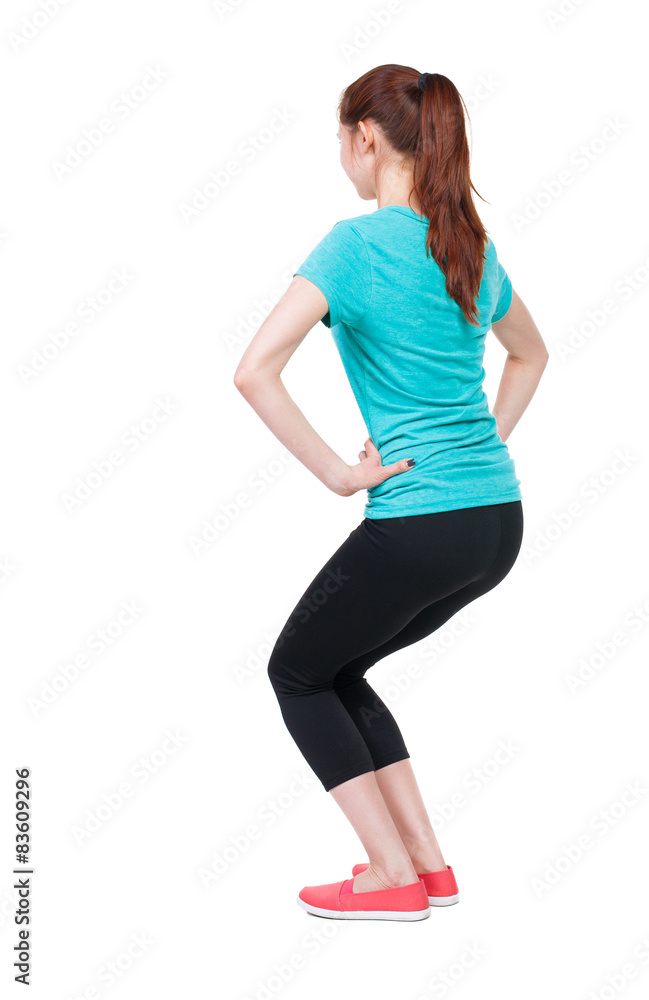 slim girl in sportswear is engaged in sports. She squats. slim girl in sportswear is engaged in sports. She squats.