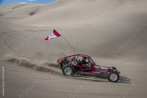 Red sand dune buggy racing by in the sand dunes