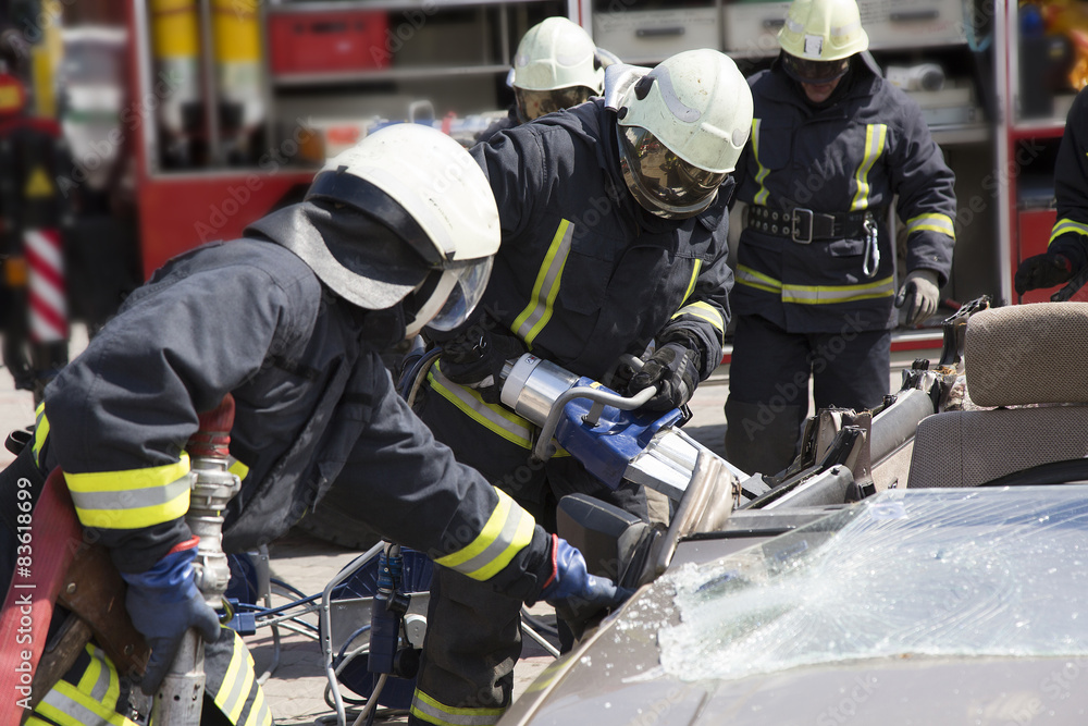 Naklejka premium firefighters with the pneumatic shears open the car doors