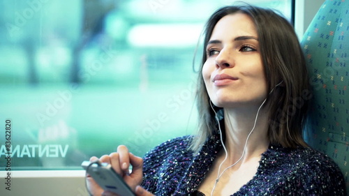 Wallpaper Mural Young, pretty woman listening to music on cellphone sitting in train 
 Torontodigital.ca