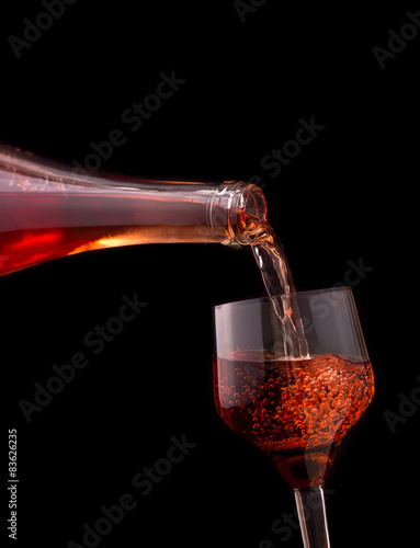 Pouring rose wine isolated on dark