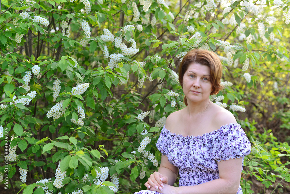 adult woman near blossoming bird cherry in the park adult woman near blossoming bird cherry in the park