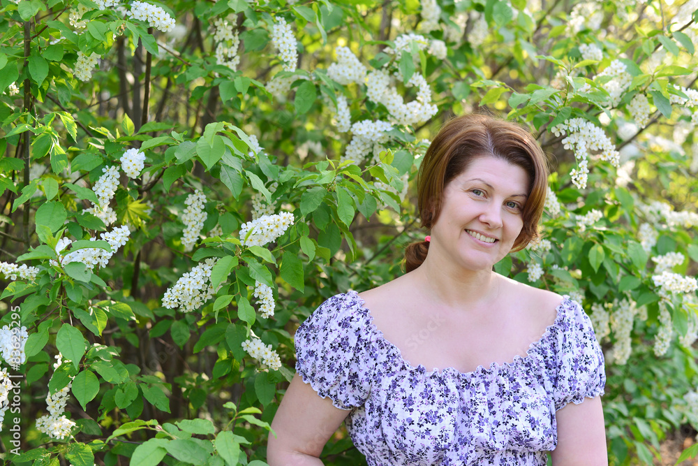 adult woman near blossoming bird cherry in the park adult woman near blossoming bird cherry in the park