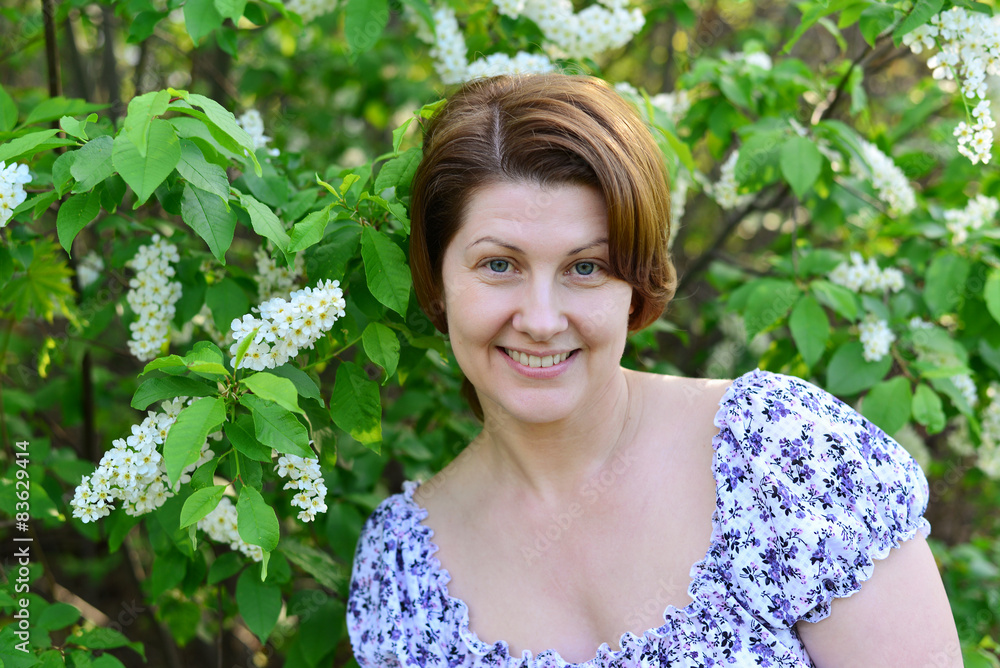 adult woman near blossoming bird cherry in the park adult woman near blossoming bird cherry in the park