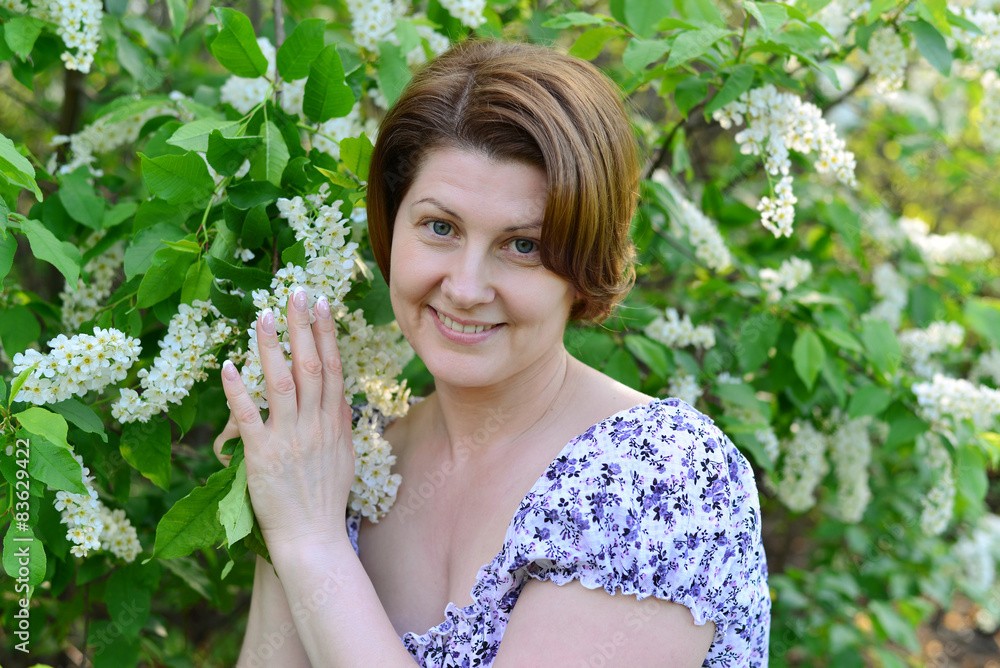 adult woman near blossoming bird cherry in the park adult woman near blossoming bird cherry in the park