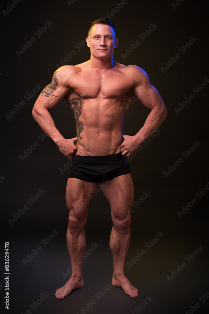 Beautiful physique bodybuilder on a dark background