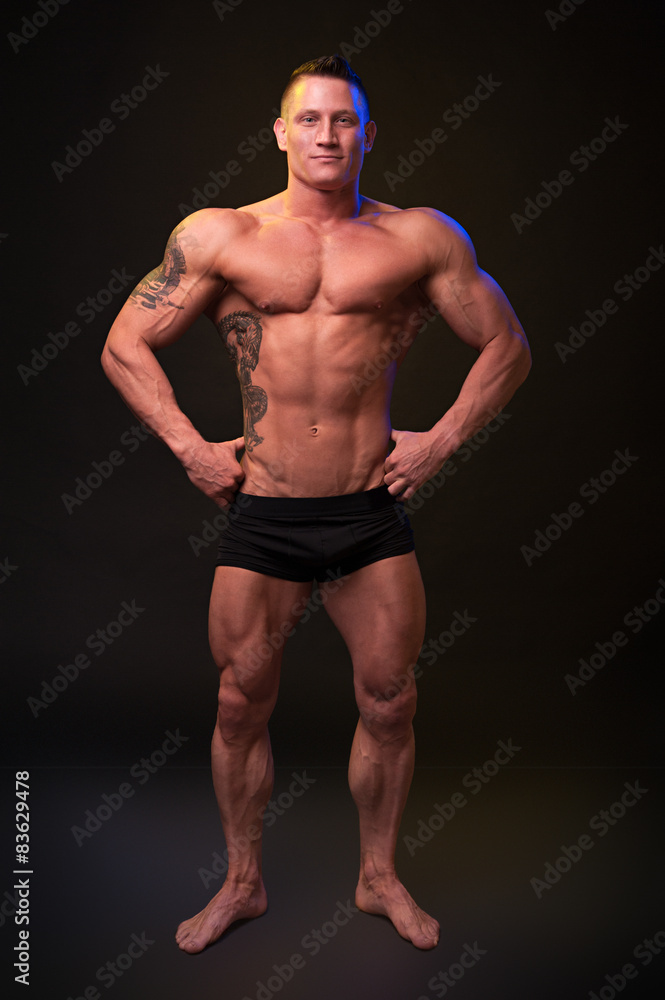 Fototapeta premium Beautiful physique bodybuilder on a dark background