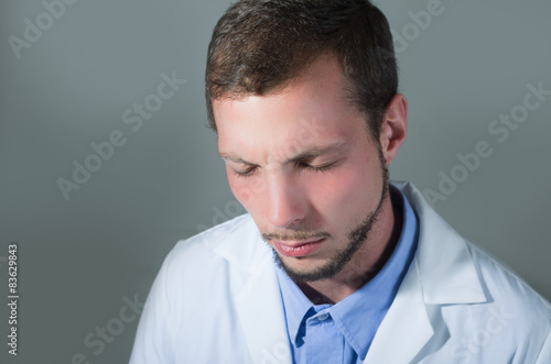 Closeup portrait of handsome young doctor with eyes closed