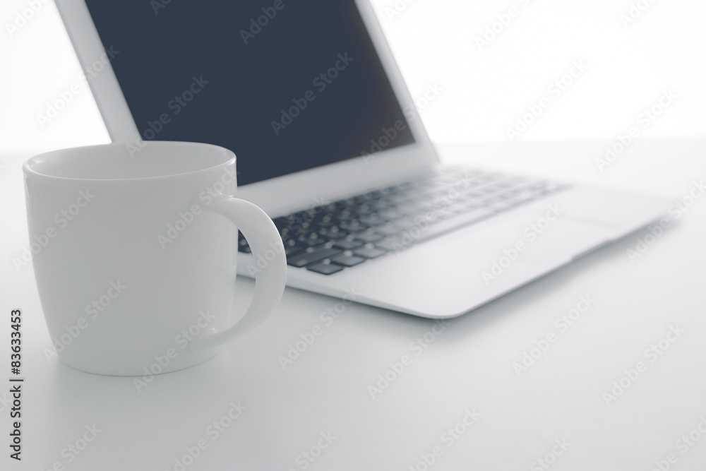 Fototapeta premium Cappuccino cup on laptop. Isolated on white background