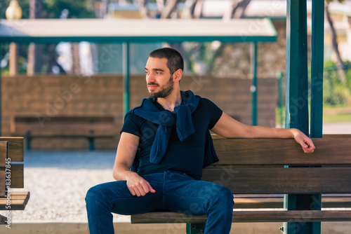 Handsome sexy and casual young man sitting on bench