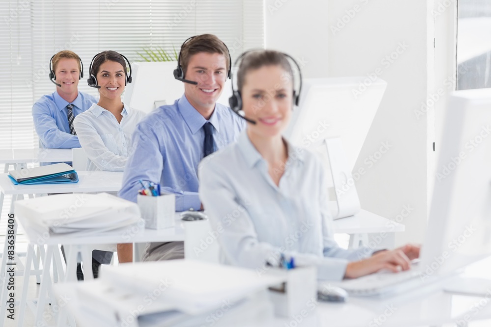 Business team working on computers and wearing headsets