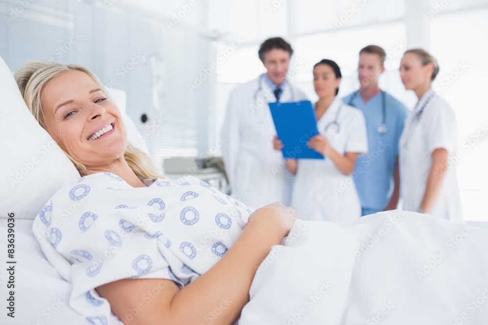 Smiling patient looking at camera with doctors behind Smiling patient looking at camera with doctors behind