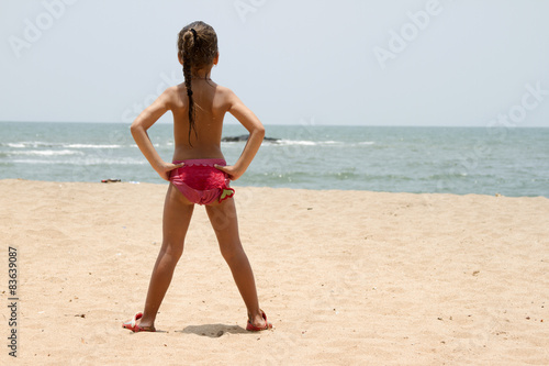 Beautiful little girl standing on the sandy beach. India, Goa