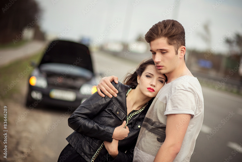 couple near a broken car on the roadside