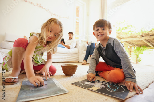 Children drawing while their father in background