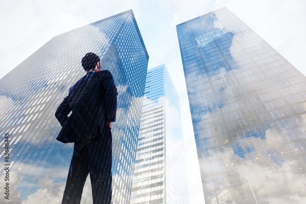 Fototapeta premium Composite image of businessman standing with hands on hips