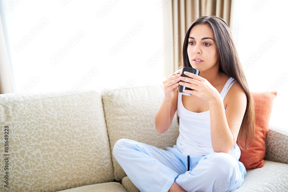 Woman staring off relaxing on couch with warm drink. Woman staring off relaxing on couch with warm drink.