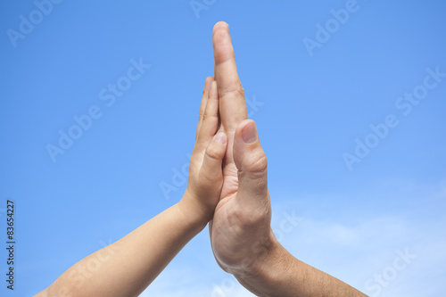 Father and son in high five gesture on a sky  background