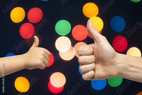father and son hands giving like on christmas lights background