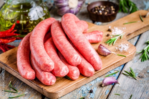 raw homemade sausages on cutting board with rosemary and garlic