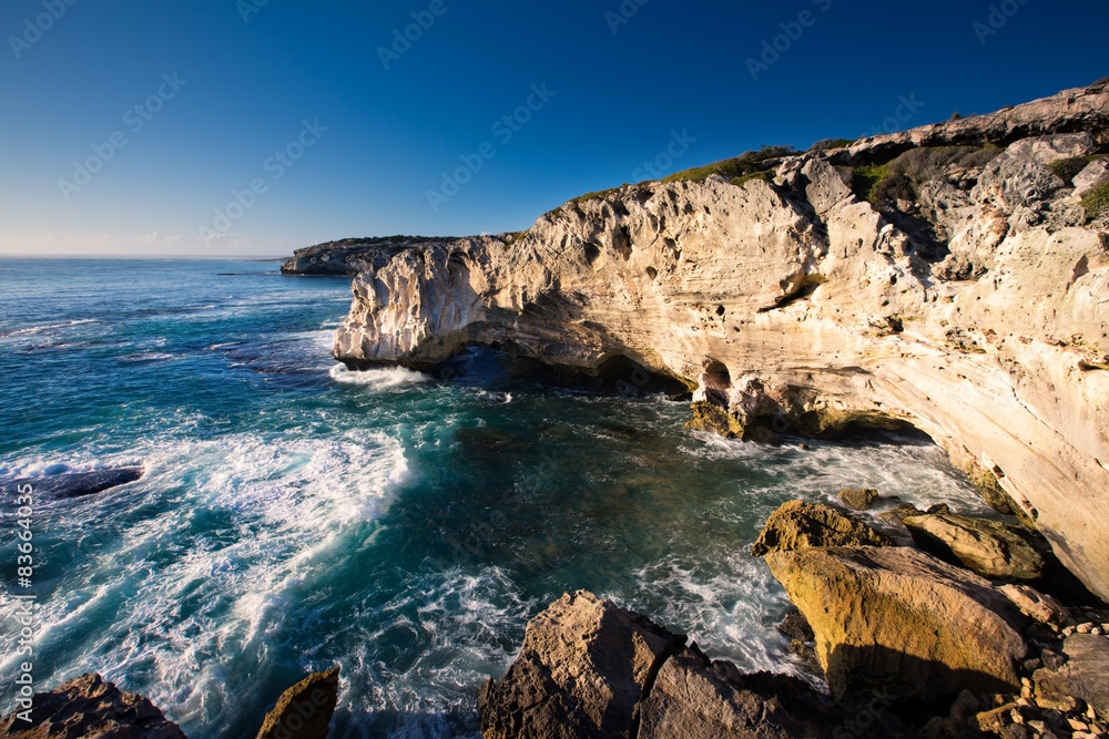Rocky cove and ocean wave crashing into an eroded arch
