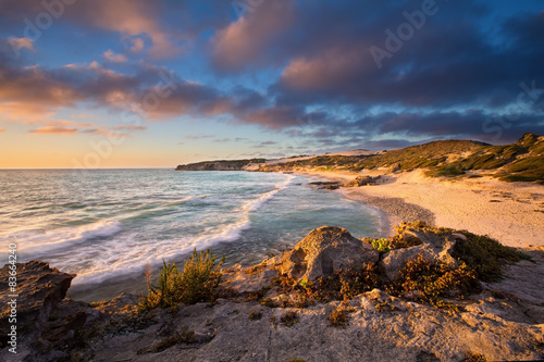 Late evening landscape of ocean over rocky shore heavy clouds bl