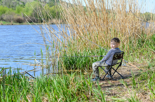 Smiling Young Boy Sitting on a Chair While Fishing