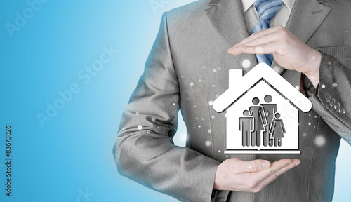 businessman protecting family in home with hands