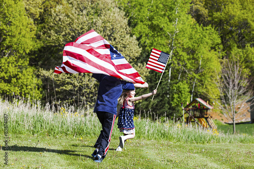 4th of july holiday: happy children with American flag running 