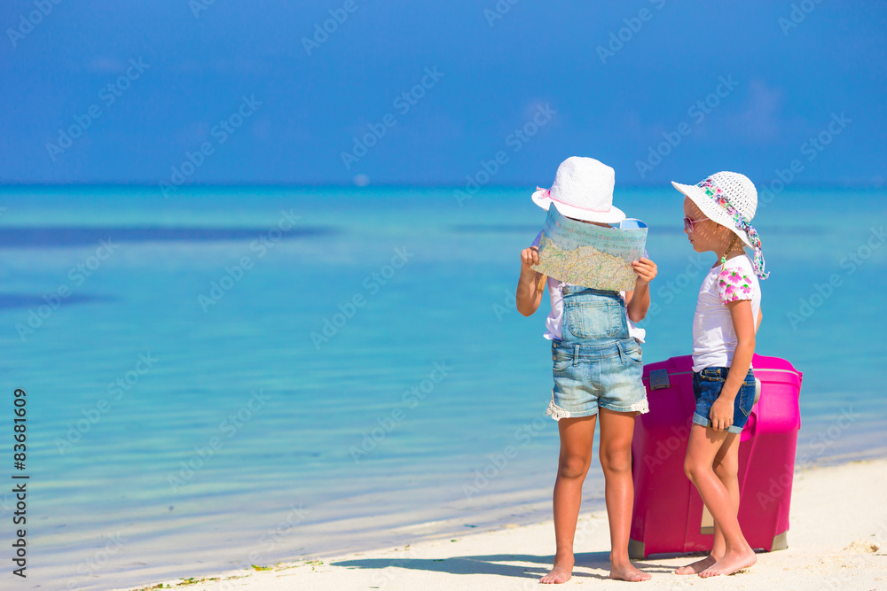 Little girls with big suitcase and map at tropical beach Little girls with big suitcase and map at tropical beach
