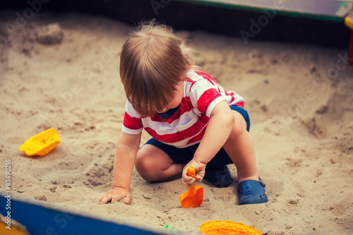 Obraz na plátně Little boy playing in sandbox