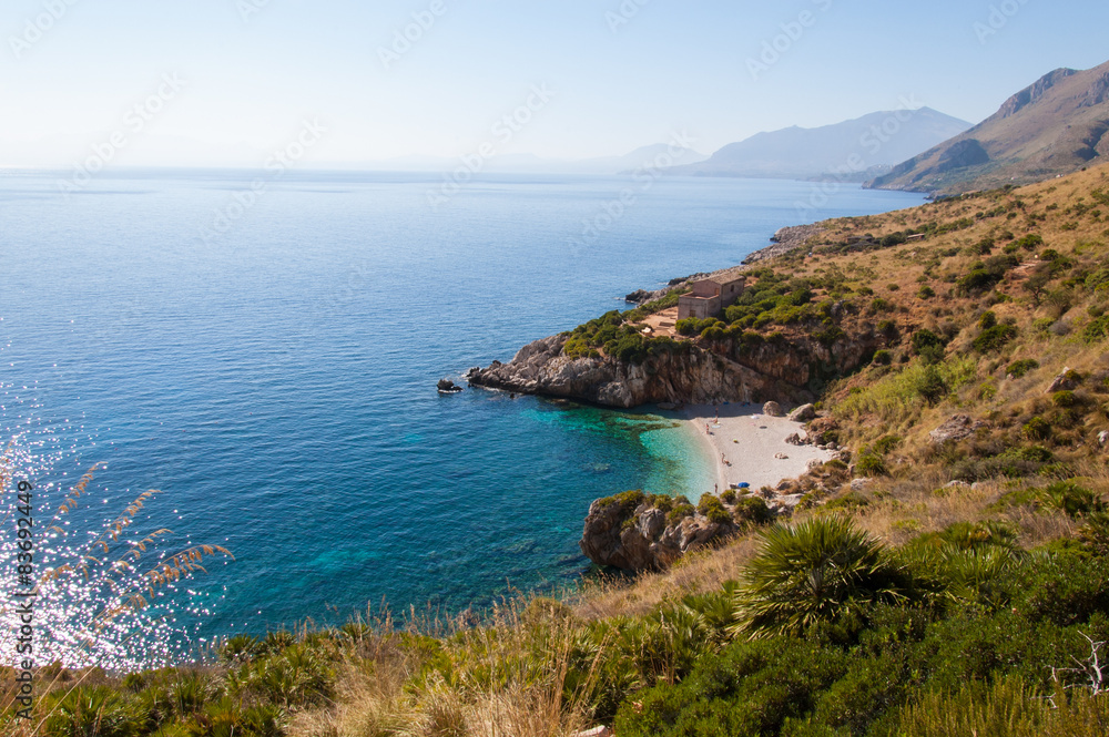 Cove with white beach and pristine blue sea in sicily