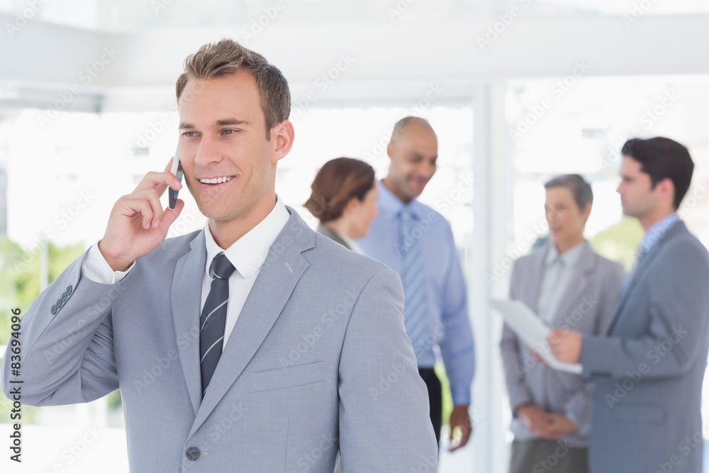 Businessman having phone call while his colleagues discussing Businessman having phone call while his colleagues discussing