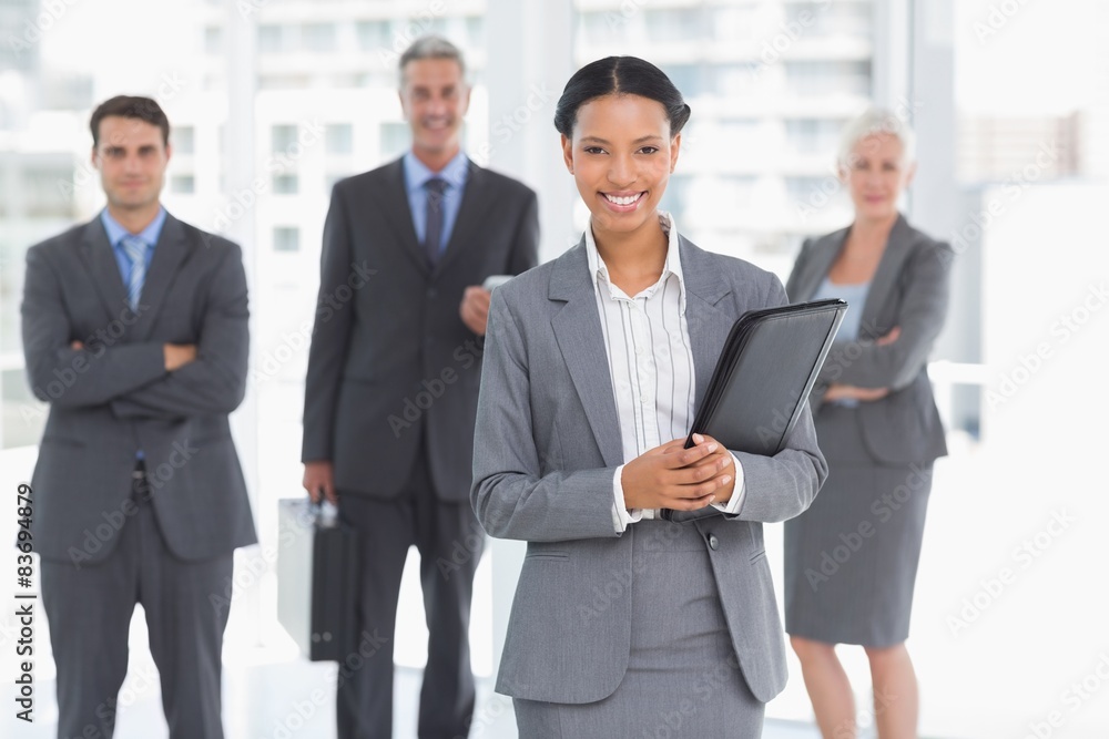 Businesswoman with colleagues behind in office Businesswoman with colleagues behind in office