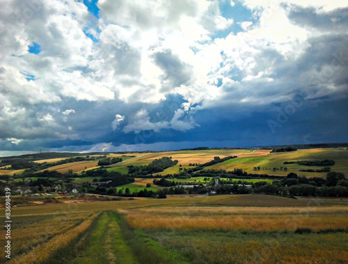 Blick auf eine Landschaft mit Feldern und dunklen Wolken