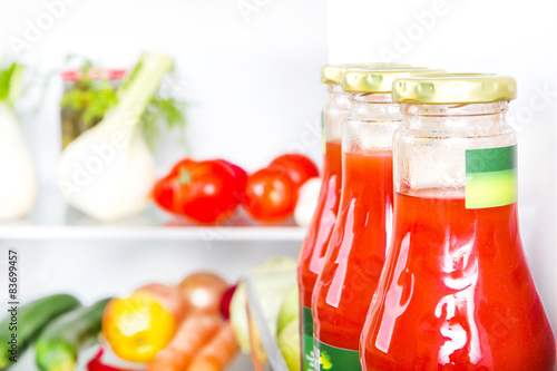 Bottle of tomato juice with fruits and vegetables at background