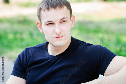 The young man sits  in park