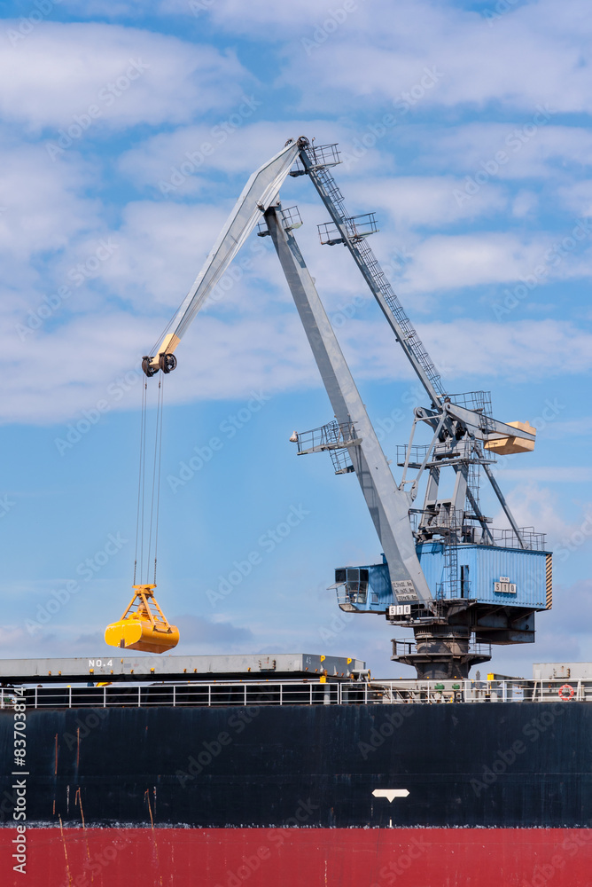 Port crane at work with the closed grabbing bucket