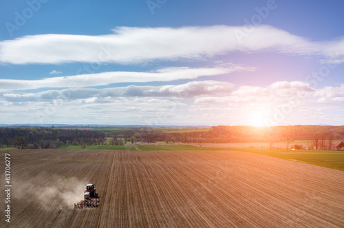 Aerial view of the sunset above the tractor harrowing the field