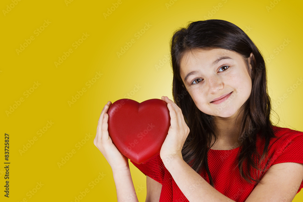 Happy, smiling little girl holding Red heart isolated on yellow background.Concept Love,Care,Health.Facial expression. Happy, smiling little girl holding Red heart isolated on yellow background.Concept Love,Care,Health.Facial expression.